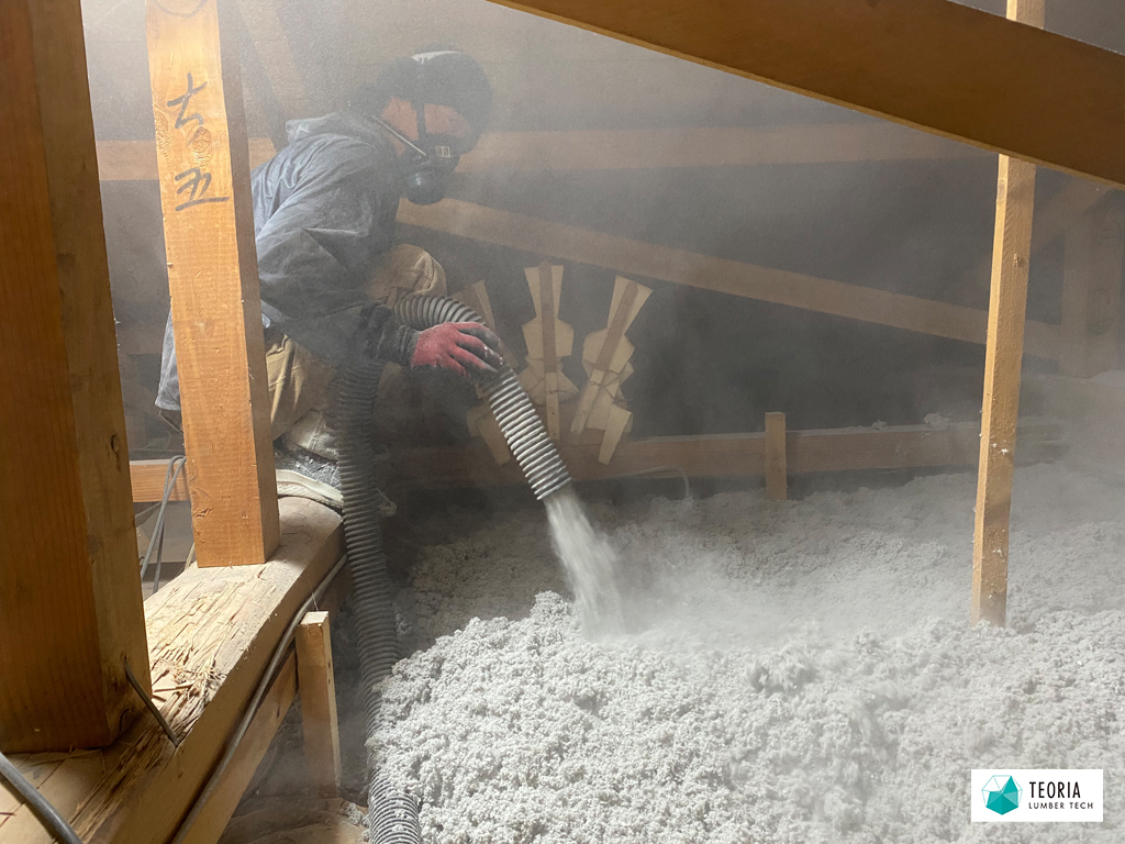小屋裏でセルロースファイバー断熱材を施工する作業員