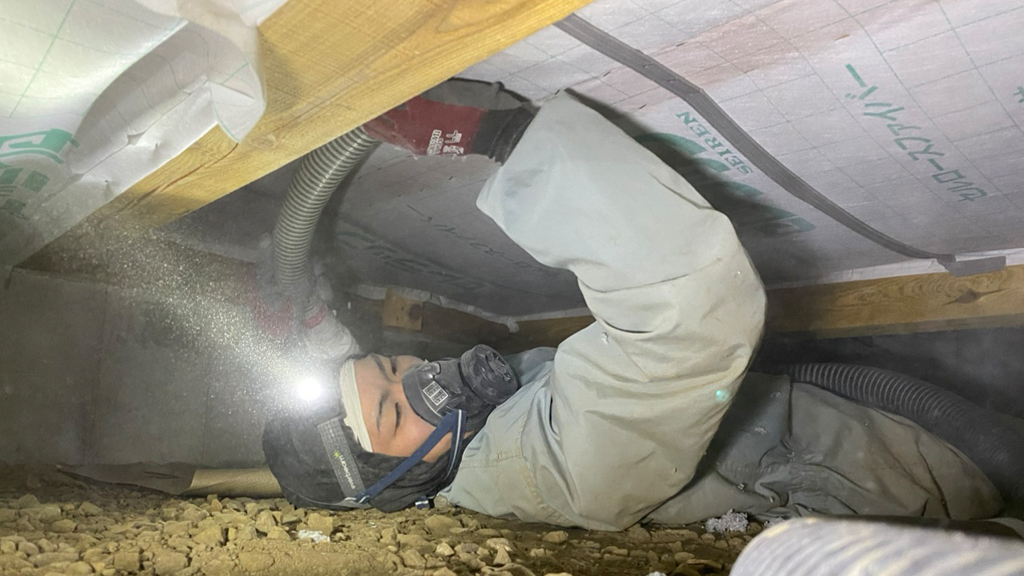 床下にセルロースファイバー断熱材を施工する作業員